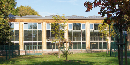 Bâtiment moderne en bois avec grandes baies vitrées dans un parc verdoyant