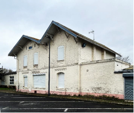 Ancienne gare à double pignon, façade crème et volets blancs fermés